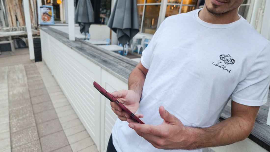 man in white shirt holding a foldable phone in red phone case