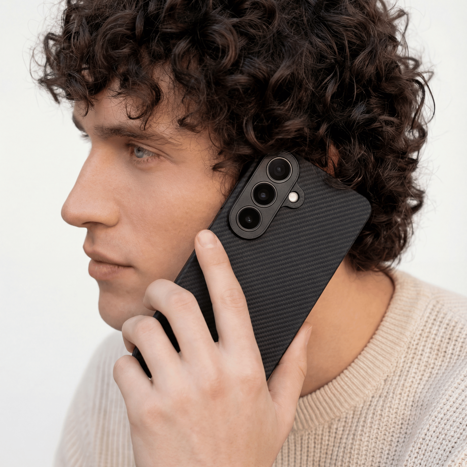 男性が耳に当てて通話しているGalaxy S26 超薄型ケース。カーボン調の質感がビジネスシーンにも馴染むデザイン。