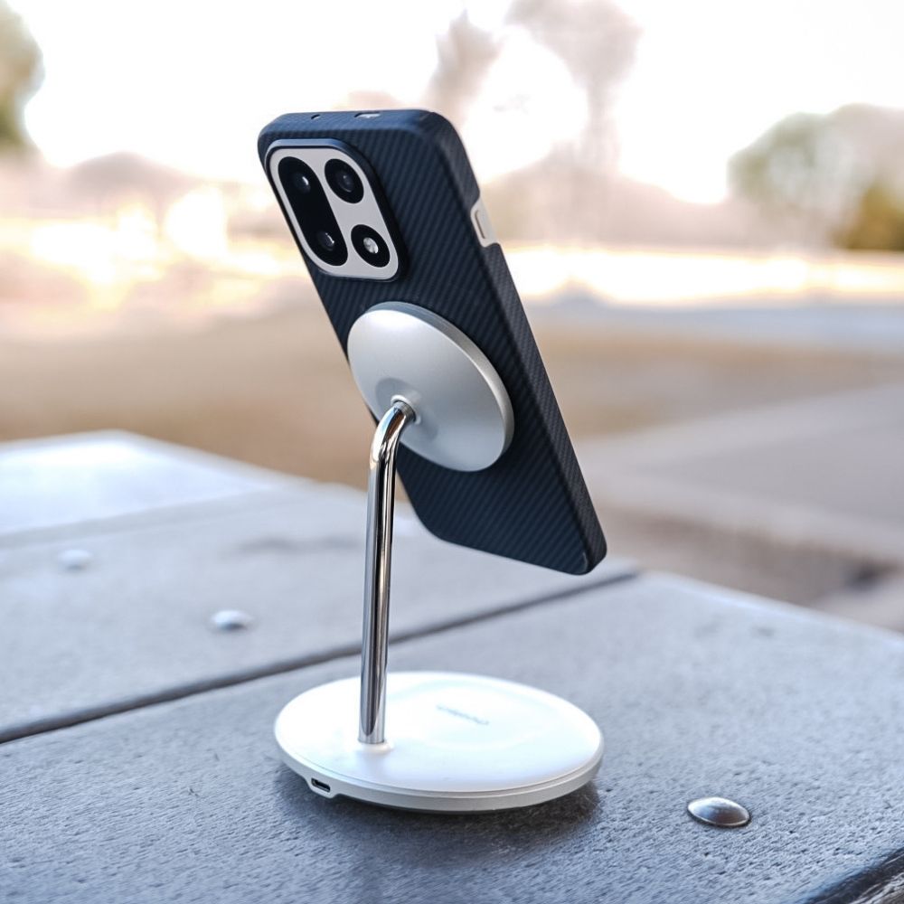 MagSafeワイヤレス充電スタンド 代替テキスト: OnePlus 15 用のThinborneアラミド繊維ケースを装着したスマートフォンが、マグネット式ワイヤレス充電スタンドに固定されている様子。屋外のテーブルの上でMagSafe機能を活用するシーン。
