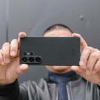 黒いカーボン調のSamsung Galaxy S25 Ultra ケースを両手で持ち、カメラを構えている人物の写真。
