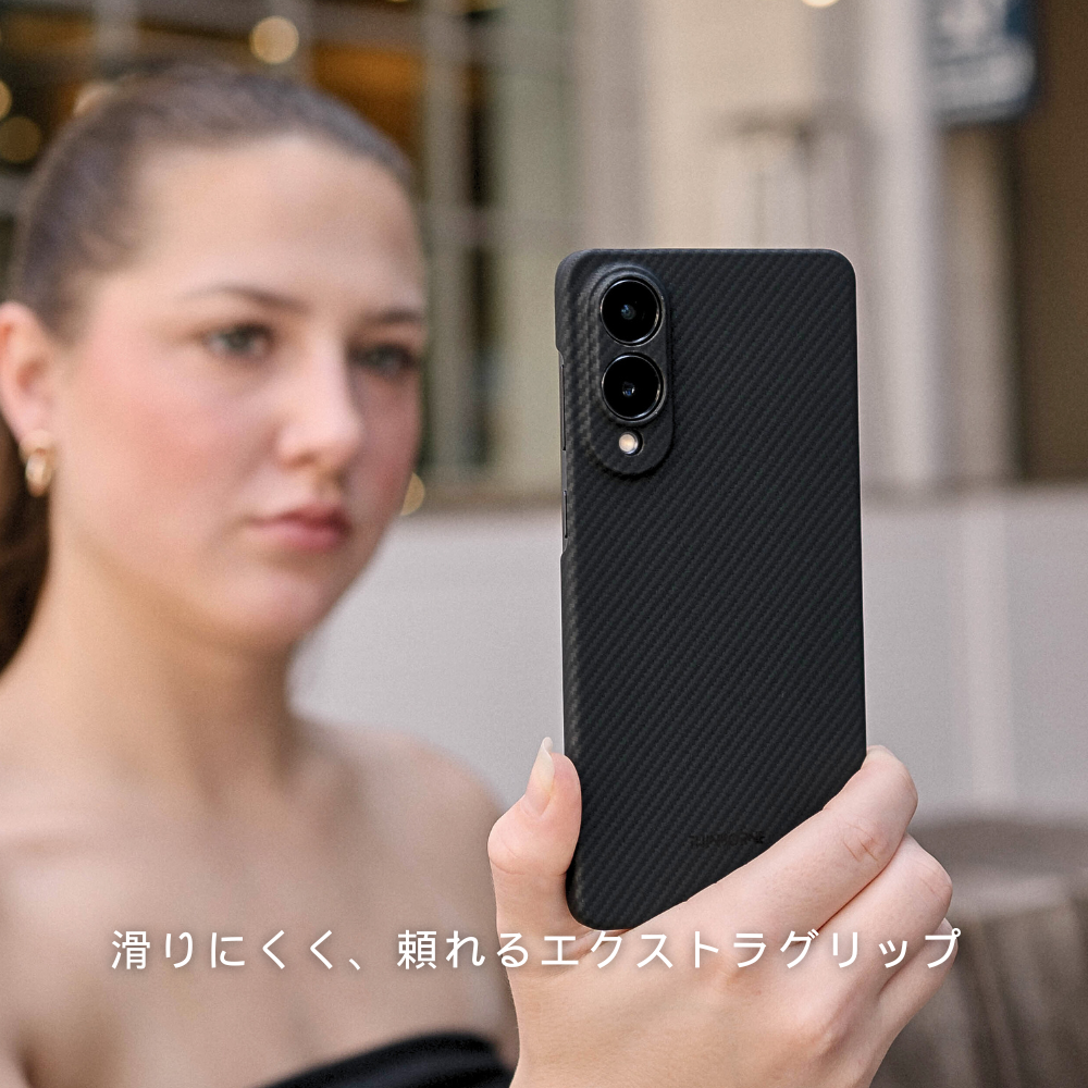 黒いカーボン調のSamsung Galaxy S25 Edge ケースを装着したスマホで、女性が自撮りをしている写真。下に「滑りにくく、頼れるエクストラグリップ」と書かれています。