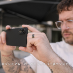  黒いカーボン調のSamsung Galaxy S25 Edge ケースを装着したスマホで、男性が写真を撮っている写真。下部に「超プレミアム・カーボンファイバー調テクスチャ」と書かれています。